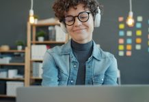 Stop the Pop-Ups: Your Guide to Ad-Free Adult Browsing Woman wearing headphones smiles while looking at laptop.