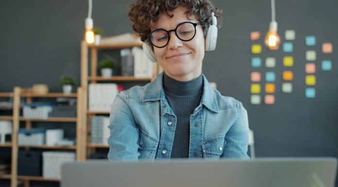 Stop the Pop-Ups: Your Guide to Ad-Free Adult Browsing Woman wearing headphones smiles while looking at laptop.